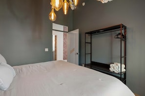 A bedroom with a bed, a wardrobe, and a hanging light fixture. - Lofted Luxury | 5 BR • Sleeps 10 • Downtown! (Frankfort)