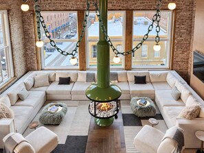 A cozy lounge area with a fireplace, seating, and large windows offering a view of the street. - Stunning Penthouse | Luxe • Sleeps 19 • Downtown! (Frankfort)