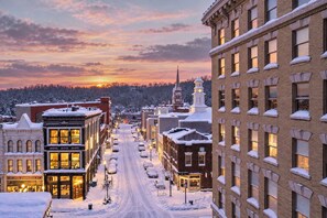 A snow-covered street lined with historic buildings, including a church with a steeple and a building with a clock tower. - Stunning Penthouse | Luxe • Sleeps 19 • Downtown! (Frankfort)