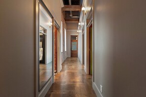 A hallway with wooden flooring, a brick wall, and a door with a glass panel. - Stunning Penthouse | Luxe • Sleeps 19 • Downtown! (Frankfort)