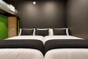 Een tweepersoonsbed met een zwart-wit dekbed, een groene accentmuur en een behang met patroon.