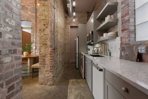 A kitchen with exposed brick walls, modern appliances, and a marble countertop. - Suite Luxury | Designer • Ideal Downtown Location! (Frankfort)