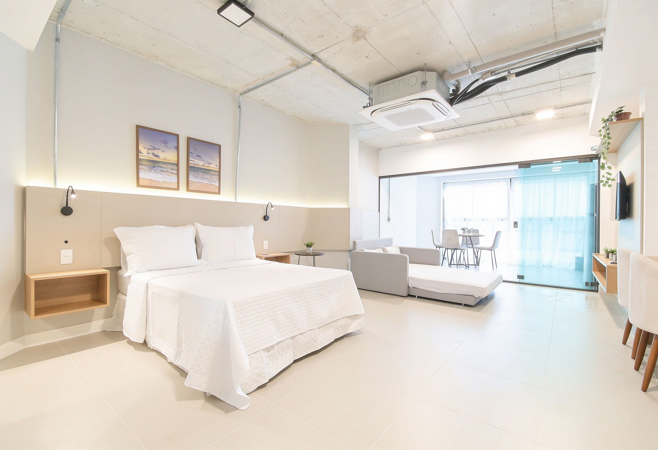 Ein modernes Hotelzimmer mit einem großen Bett, einer Couch, einem kleinen Tisch und einem Fernseher.
