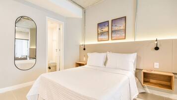 A bedroom with a large bed, a mirror, two bedside tables, and a wall-mounted light fixture.