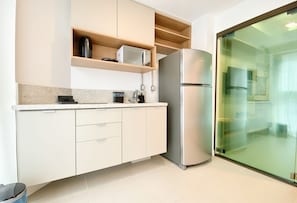 A modern kitchen with a built-in microwave, a stainless steel refrigerator, and a glass door leading to a balcony. - Silo 240 in Recife Antigo With Two Leisure Rooftops, Pools, Gym, Coworking and Sea View, Near Marco Zero by Carpediem (Recife)