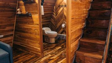 A wooden interior with a wooden staircase, a toilet, and a blue chair.