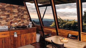 A kitchen with a stone backsplash, wooden cabinets, and a view of the mountains through large windows.