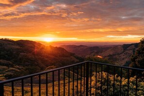 A sunset view from a balcony with a railing, overlooking a valley with hills and trees. - Torremar House Monteverde (Provincia de Puntarenas)