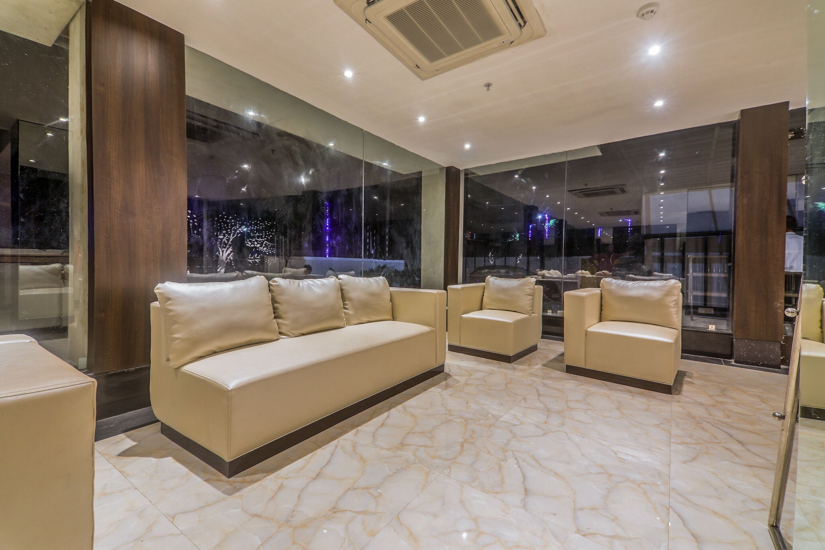 A modern hotel lobby with a marble floor, leather sofas, and large windows offering a view of the cityscape.