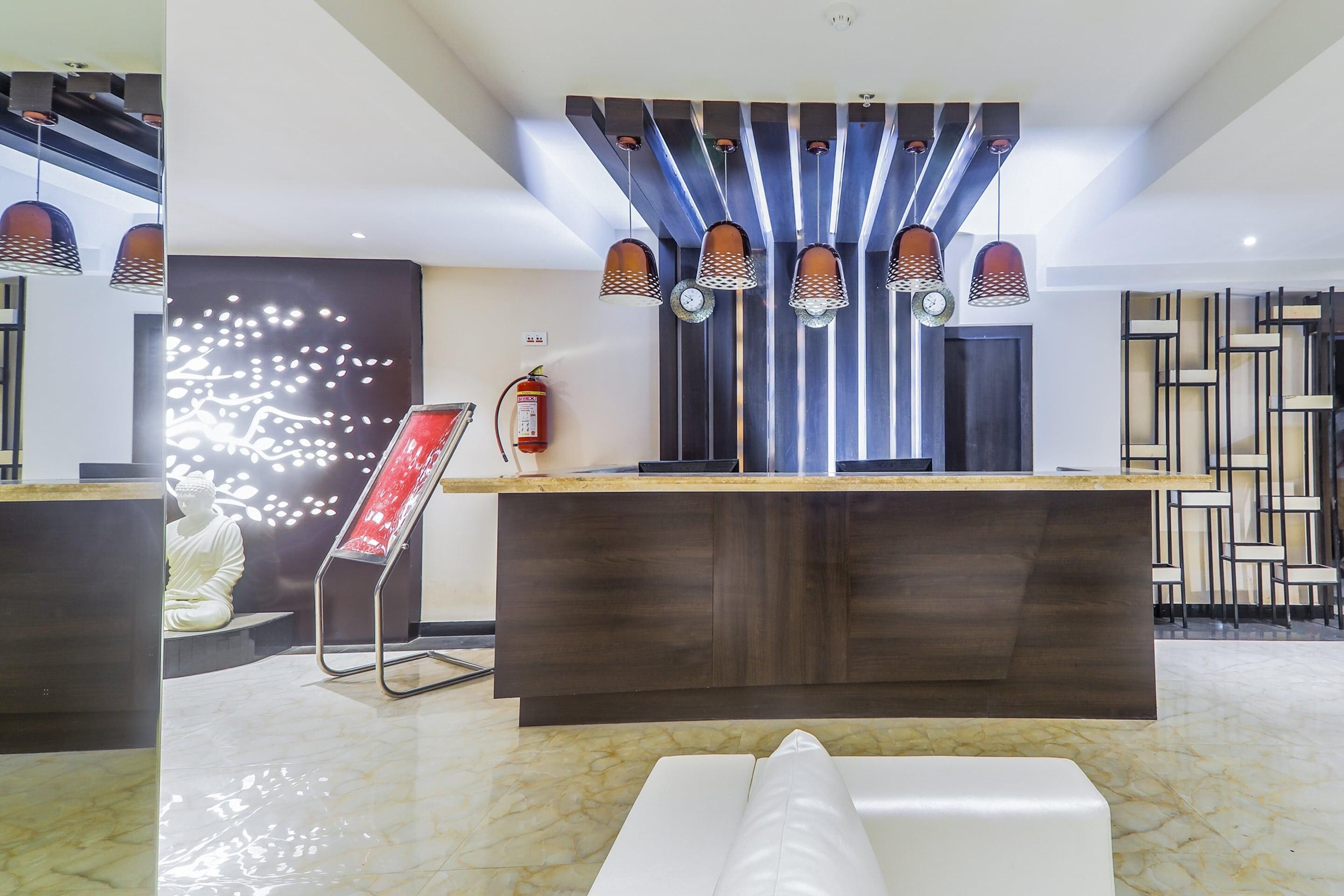 A reception area with a marble floor, a reception desk, a fire extinguisher, and a decorative wall with a light fixture.
