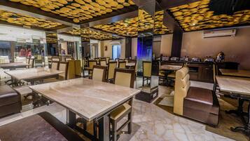 Un interior de restaurante con suelo de mármol, varias mesas y cabinas.