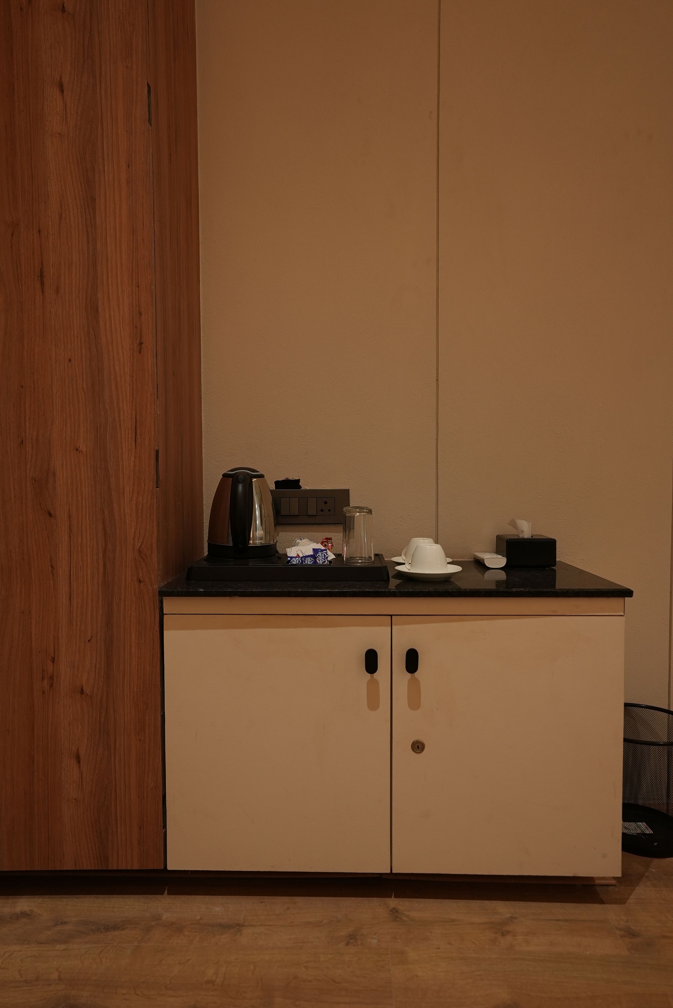 A kitchenette with a coffee maker, a glass jar, and a plate with cups.