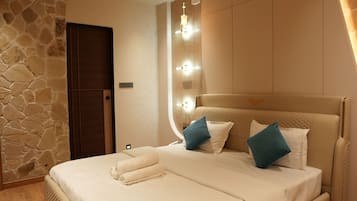 A bedroom with a bed, a ceiling fan, a stone wall, and a door.