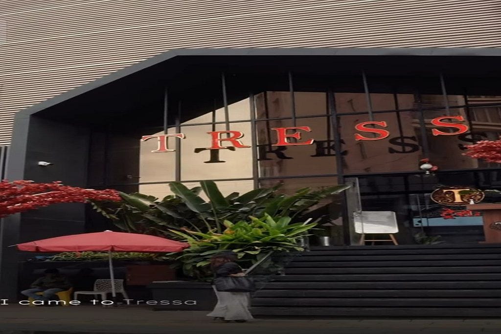 A building entrance with the name 'TRESS' displayed prominently.