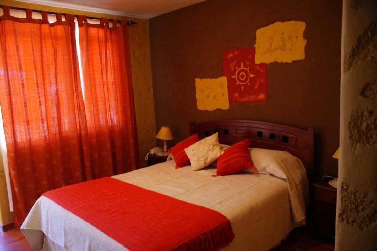 A hotel room with a bed, a nightstand, a lamp, and a wall with a map.