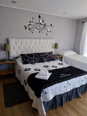 A neatly made bed with a floral bedspread, a decorative wall piece, and a bedside lamp.