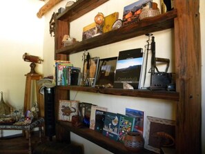 A wooden shelf with various items including books, a globe, and decorative objects. - Hostal Apuwara (Combarbala)