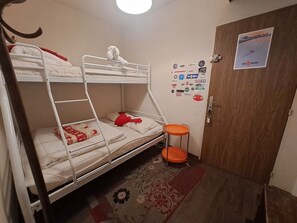 A bunk bed room with a small orange stool, a door with a poster, and a patterned rug. - Ideal studio near slopes - 4 guests (Les Deux Alpes)