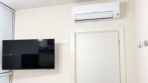 A room with a flat-screen TV mounted on the wall, a white door, and an air conditioning unit above the door. - Coccole Sottomarina by Ca-Sa Check (Chioggia)