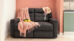 A dark grey sofa with a pink knitted throw blanket and two yellow roses. - Coccole Sottomarina by Ca-Sa Check (Chioggia)