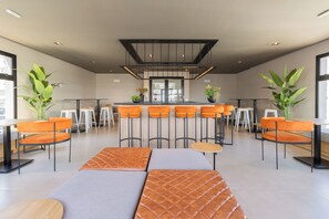 A modern bar area with high stools, a central bar counter, and seating with cushioned benches. - Nik by Bhomy (São Paulo)