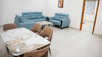 Una habitación moderna con sofá modular, una mesa de mármol y persiana con estampado.