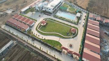 An aerial view of a residential complex with multiple buildings, a swimming pool, and landscaped areas.