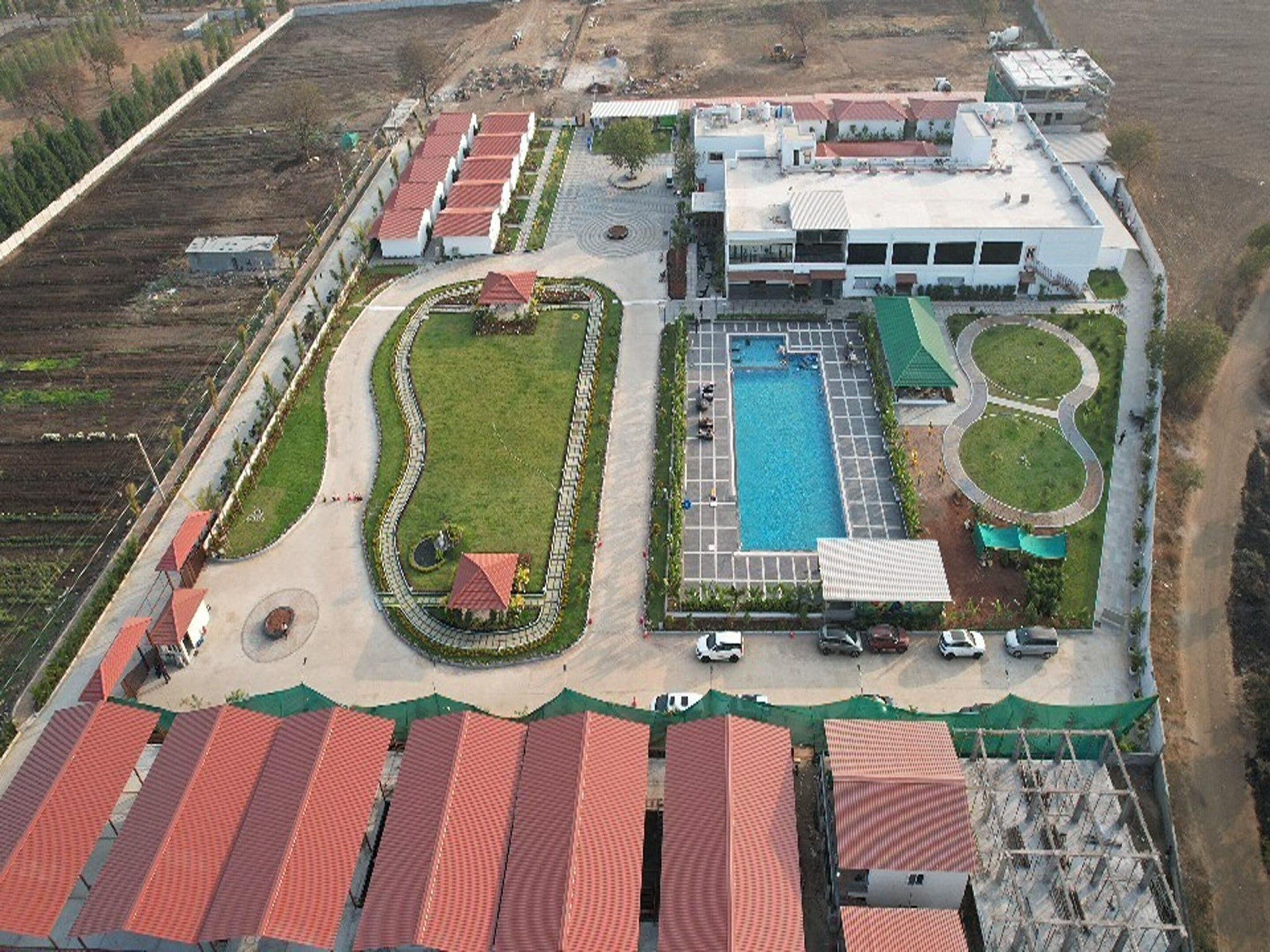 An aerial view of a hotel with a swimming pool, multiple buildings, and a landscaped area.