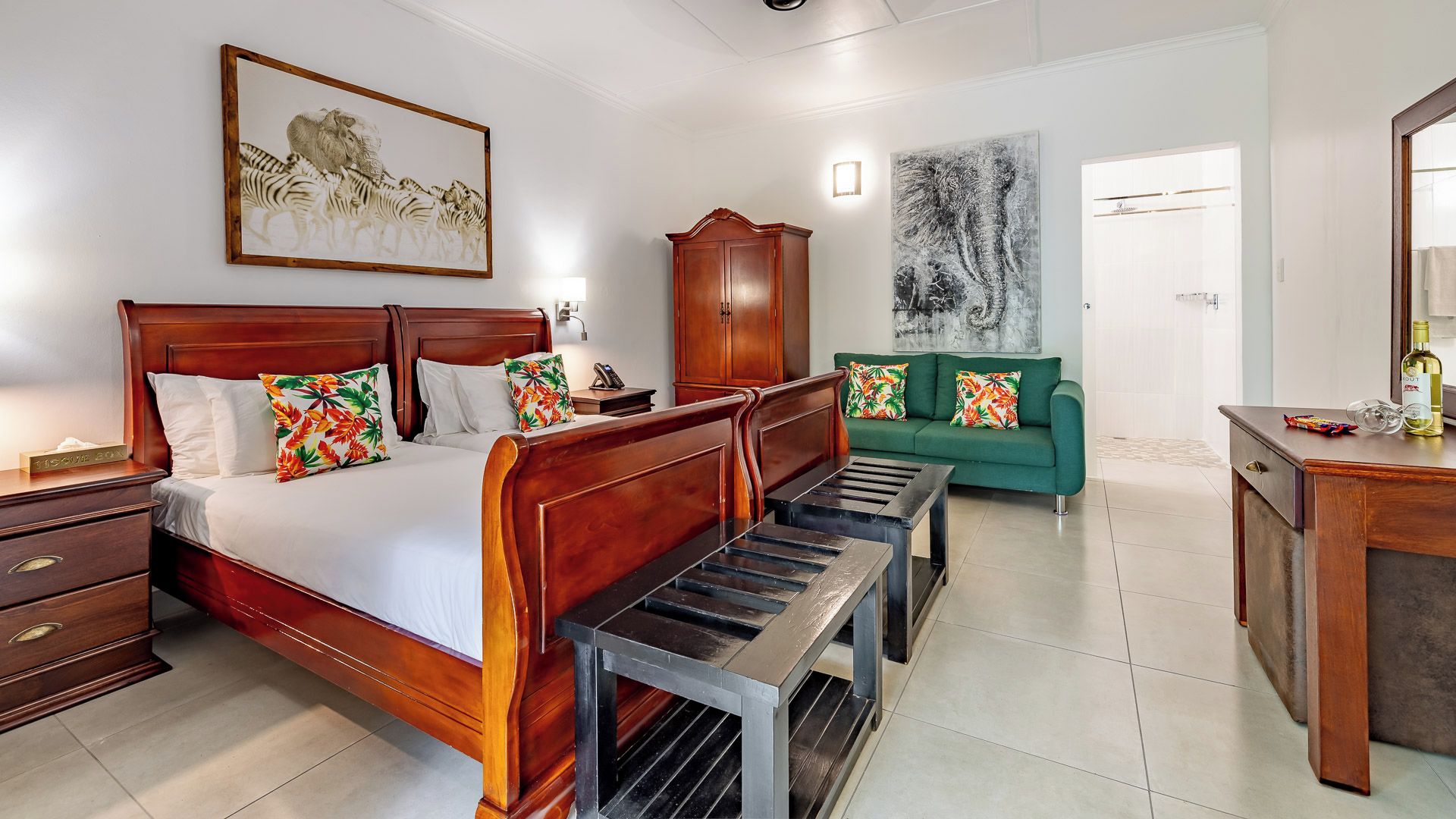 Una habitación de hotel con una cama de madera, un sofá verde, un armario de madera y un cuadro en la pared.