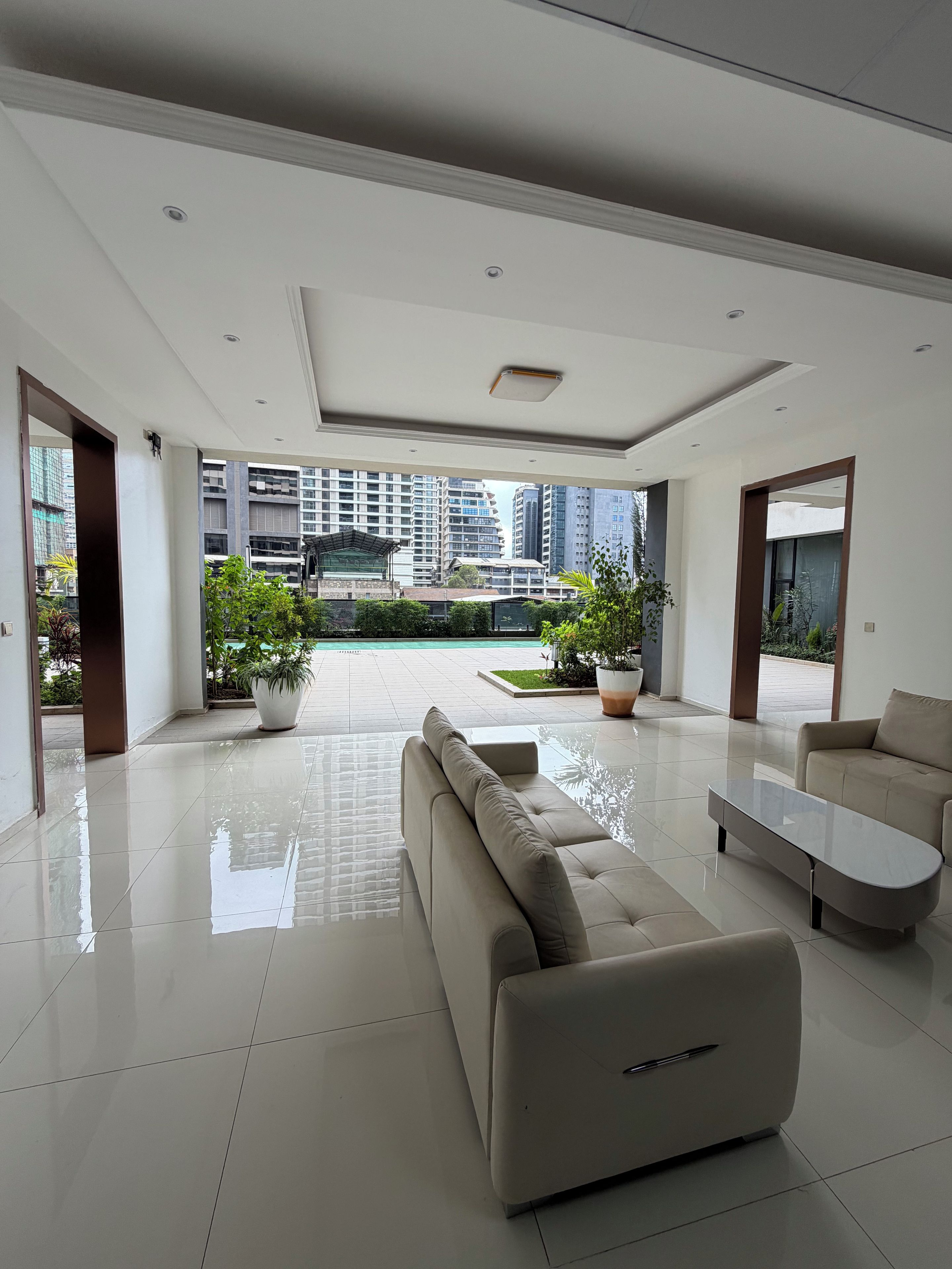 A spacious living area with a modern sofa, a coffee table, and a view of a cityscape through large windows.