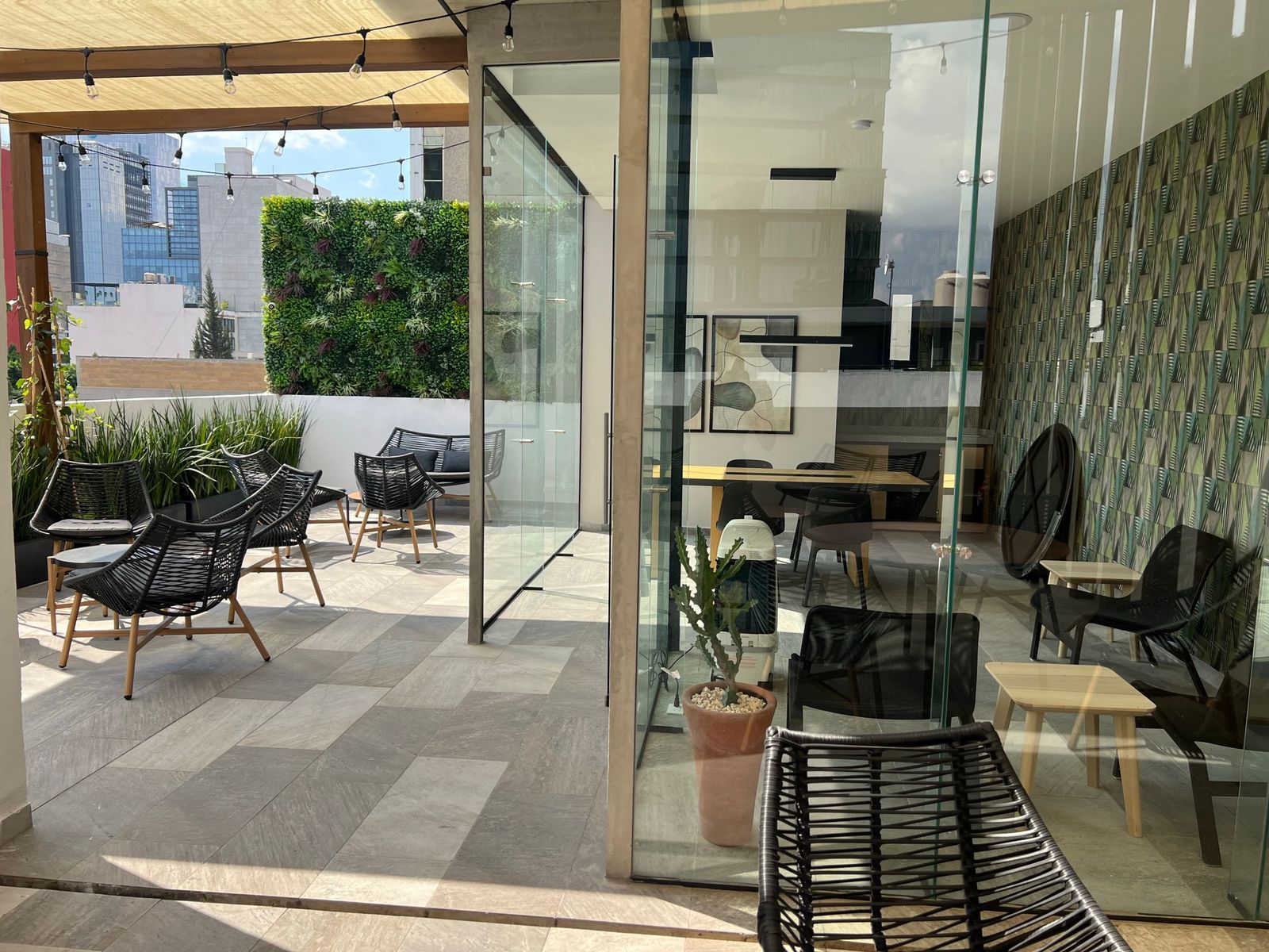 A modern interior with glass walls, a seating area with wicker chairs, and a view of the cityscape.