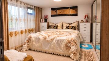 Een slaapkamer met een groot bed, een kaptafel, een spiegel en een raam met gordijnen.