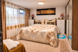 A bedroom with a large bed, a dresser, a mirror, and a window with curtains.