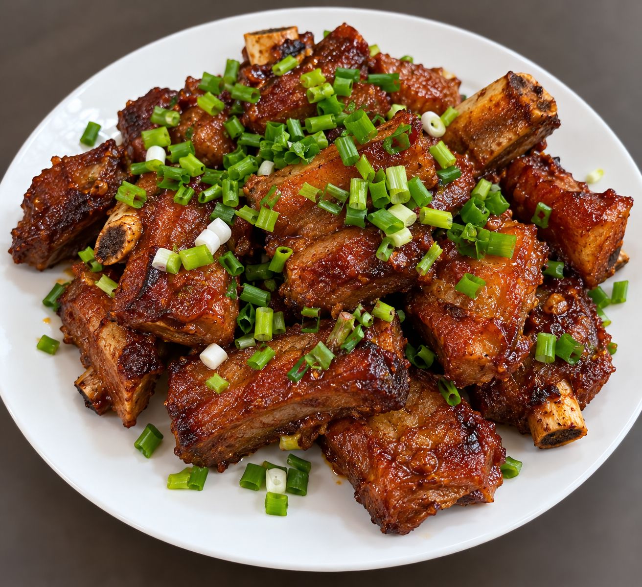 A plate of barbecued ribs garnished with chopped green onions.