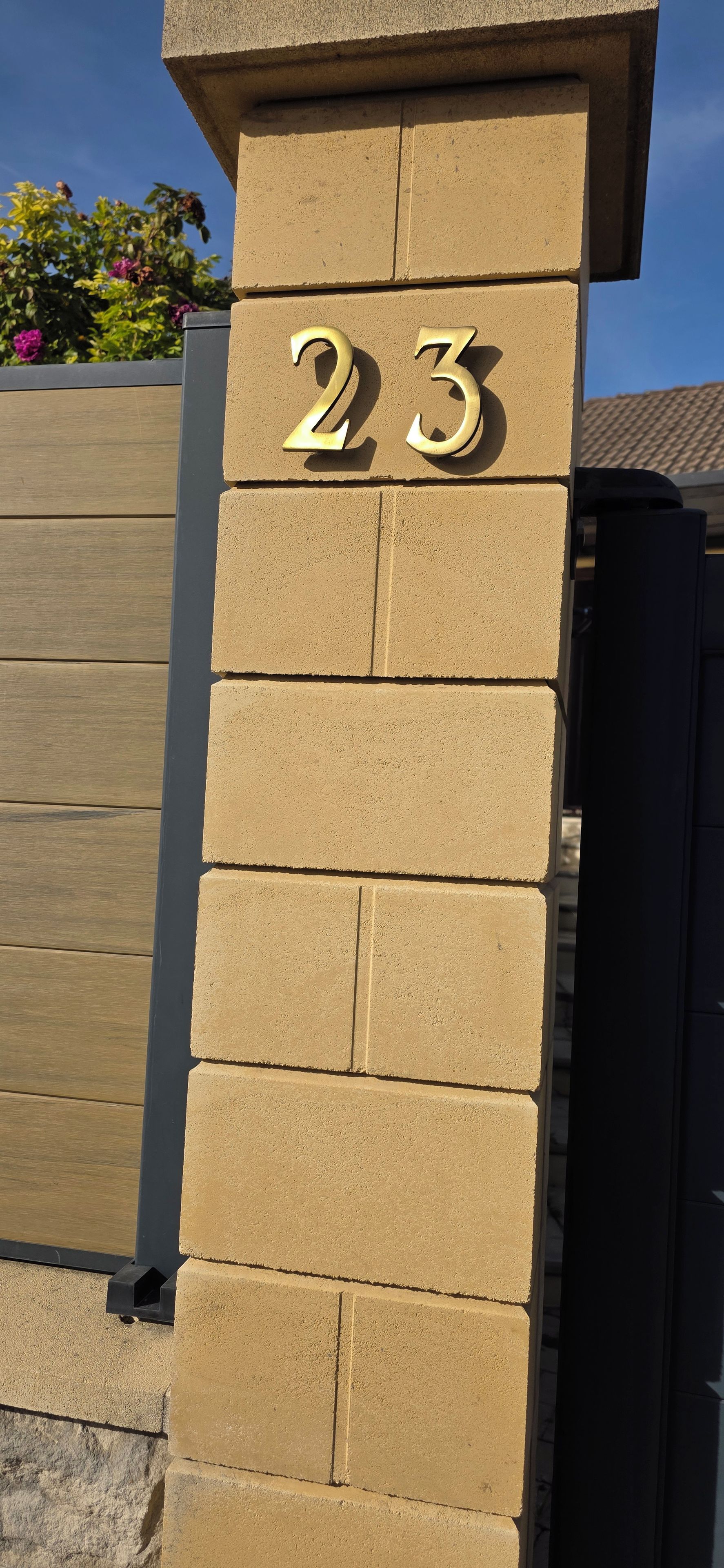 Un pilier en briques de couleur beige, sur lequel est inscrit le chiffre « 23 » en doré.