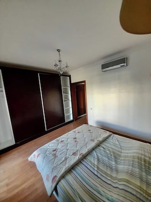 Ein Schlafzimmer mit einem Bett, einem Kleiderschrank, einer Chandelüster und einer Klimaanlage.