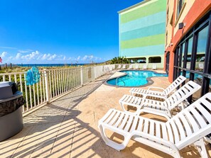 A pool area with lounge chairs, a barbecue grill, and a view of the ocean. - Cute 2 Bed 2 Bath at Harbor Place - Fall Specials! (Orange Beach)