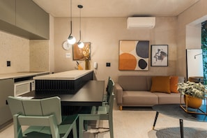 A modern kitchen with a dining area, a sofa, and a coffee table. - Nun by Bhomy (São Paulo)