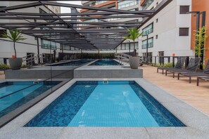 Une piscine intérieure moderne, dotée de plusieurs couloirs de nage, entourée d’espaces de détente et agrémentée de plantes en pot.