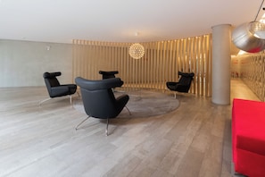 Een modern interieur met drie zwarte stoelen, een ronde glazen tafel en een bijzondere plafondlamp.