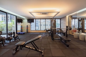 A gym with various exercise equipment, large windows, and a view of buildings outside. - Nun by Bhomy (São Paulo)