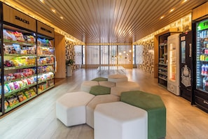 Een modern interieur met snackschapjes, zitgedeeltes en een drankautomaat.