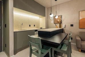 Een moderne keuken met een centraal eiland, een eethoek met tafel en stoelen, en een zithoek met een bank.
