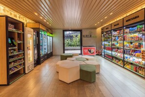 L’intérieur d’une épicerie moderne, avec des espaces aménagés pour s’asseoir, des rayons réfrigérés et une grande variété de produits exposés sur des étagères.