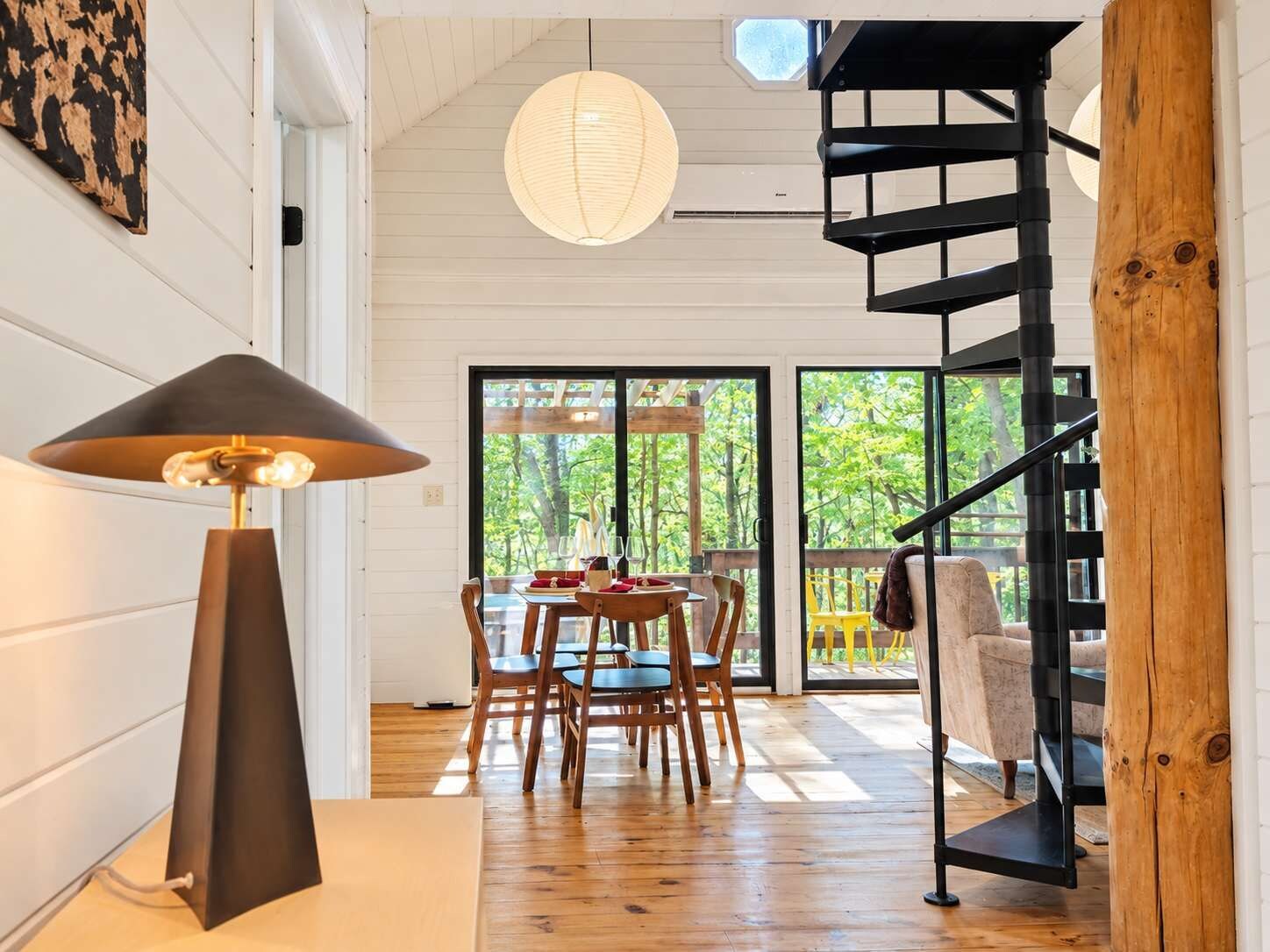 Een modern interieur met een eethoek, een trap en uitzicht op het omliggende landschap.