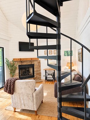 Un intérieur moderne agrémenté d’un escalier en colimaçon, d’une cheminée et d’un coin salon confortable.