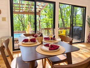 Une table à manger dressée pour quatre personnes, avec des sets de table, des verres à vin et des serviettes pliées.