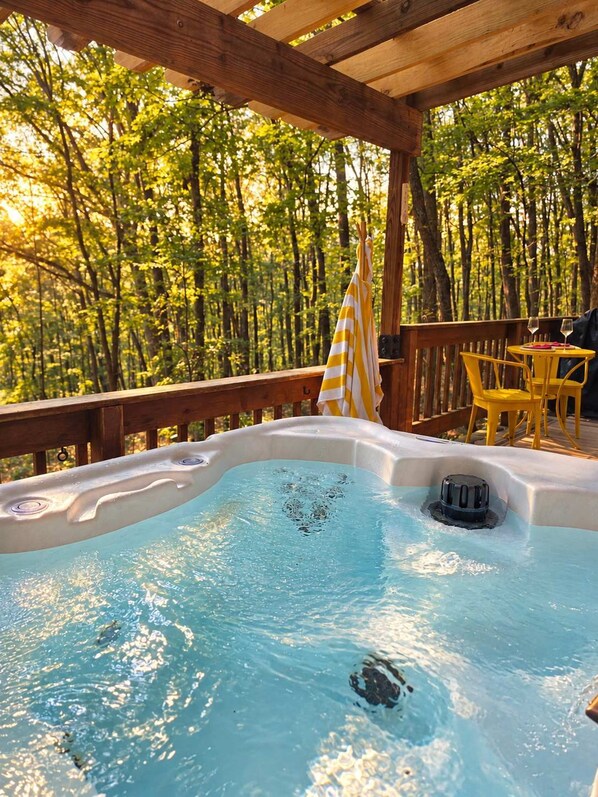 Een hottub op een houten terras, omringd door bomen.