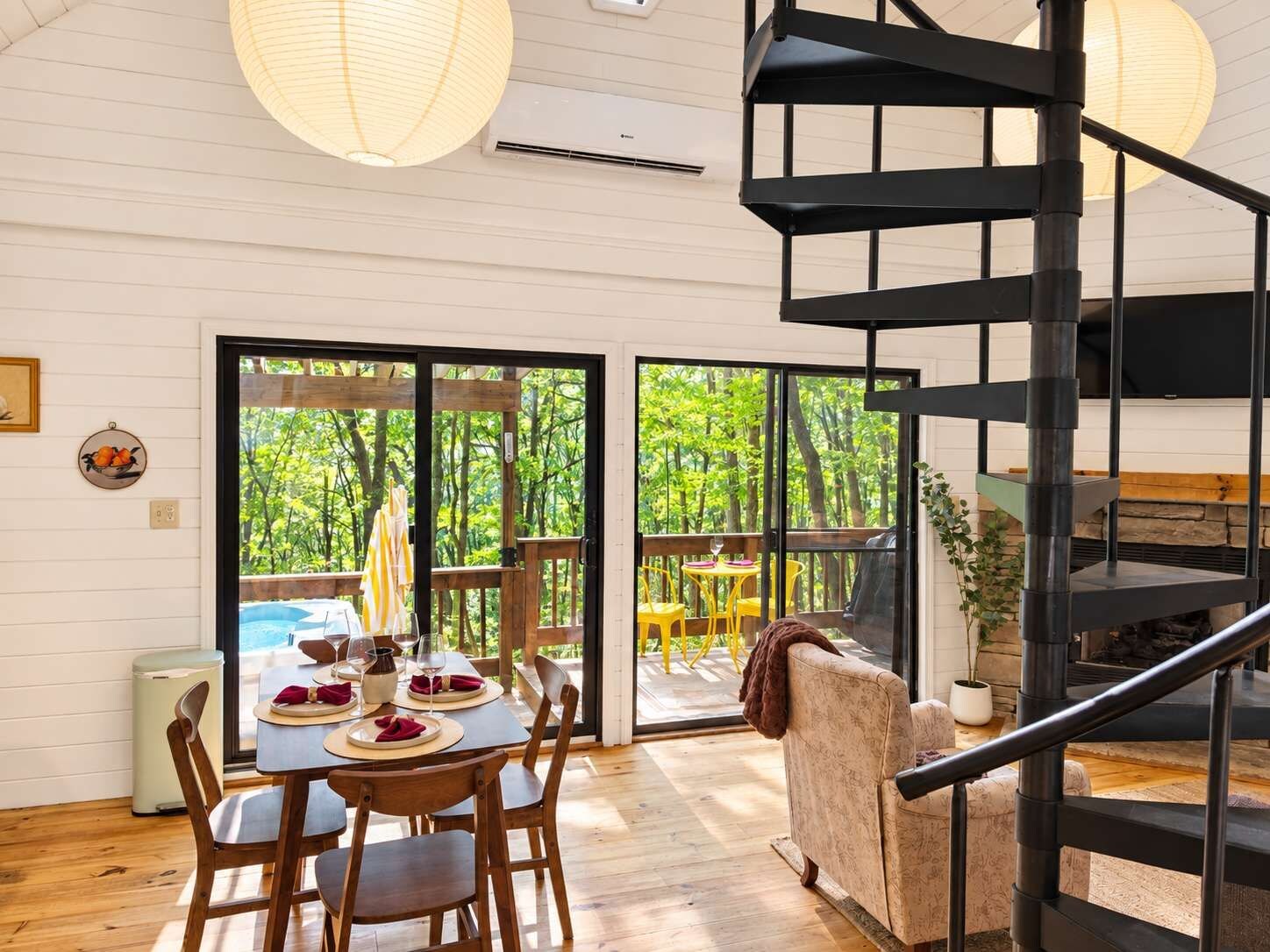 Een modern interieur met een eethoek, een trap en uitzicht op een weelderige tuin.