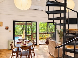 Un interior moderno con comedor, una escalera y vistas a un jardín exuberante.